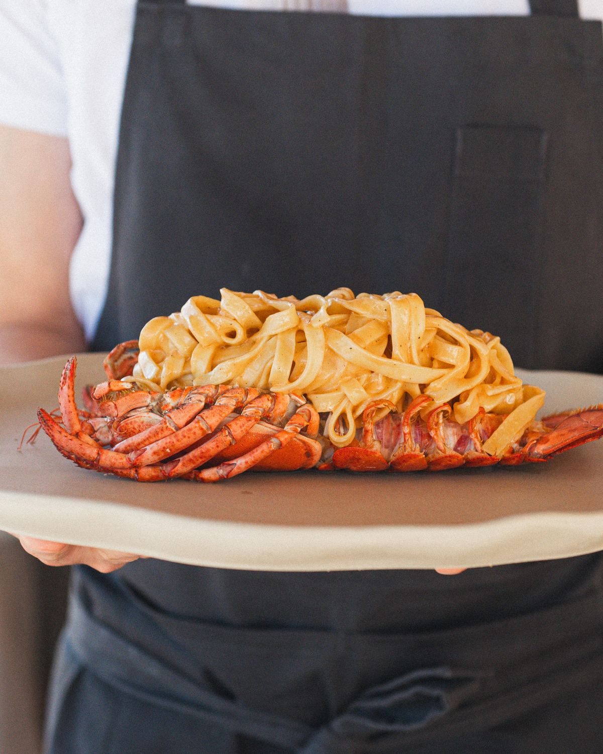 Un camarero lleva a la mesa tagliatelle con bogavante